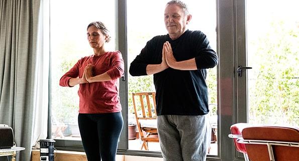 elderly couple doing yoga indoors