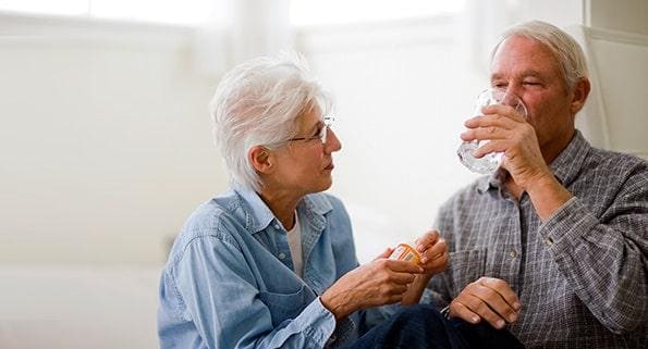 elderly man being given Bayer® Aspirin by wife
