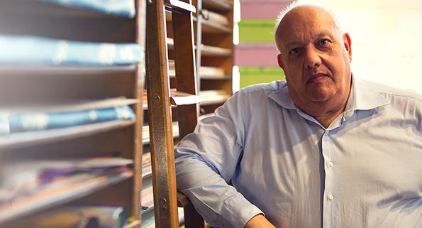 older man leaning against a ladder by shelves