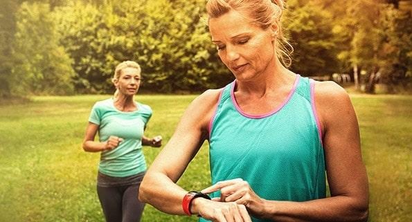 woman running and checking fitness monitor