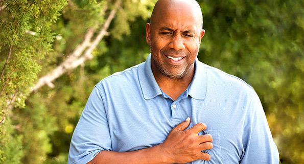 a man grimacing while clenching his heart